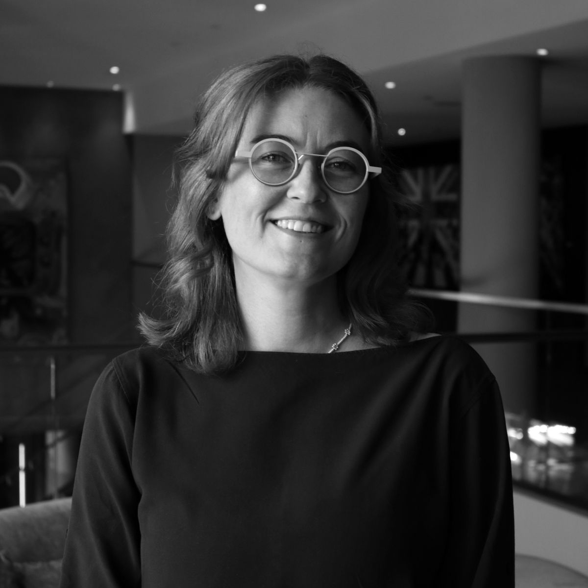 Erin Grayson. Headshot of Erin Grayson wearing a long sleep top and glasses.