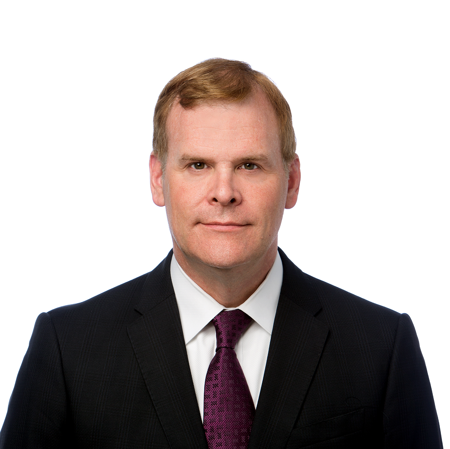John Baird. Headshot of John Baird wearing a black suit and a dark purple tie. He is posing in front of a plain white background.