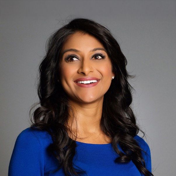 Rinki Sethi. Headshot of Rinki Sethi wearing a bright blue top. She is smiling and posing in front of a plain grey background.