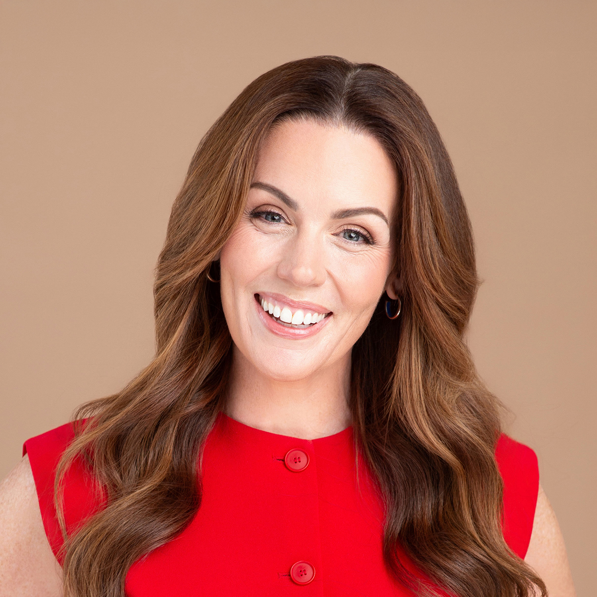 Dr. Robyne Hanley-Dafoe. Headshot of Dr. Robyne Hanley-Dafoe, smiling, wearing a red short-sleeve top and posing in front of a light brown background.
