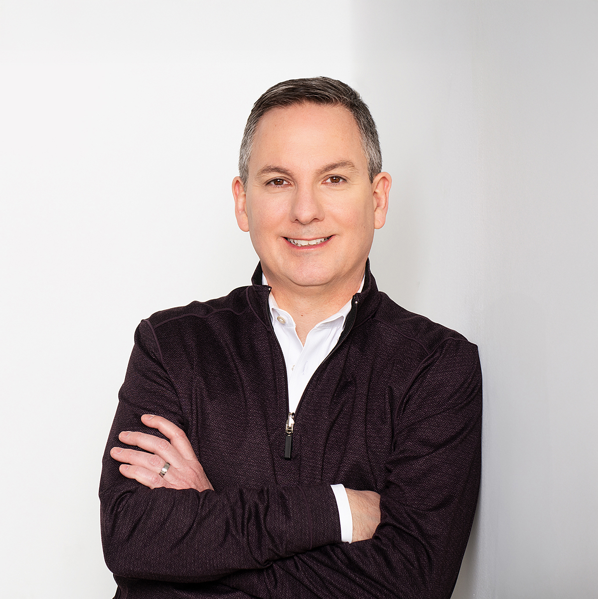 Dan Chuparkoff. Headshot of Dan Chuparkoff wearing a black jacket over a white shirt. He is standing in front of a white background and has his arms crossed.