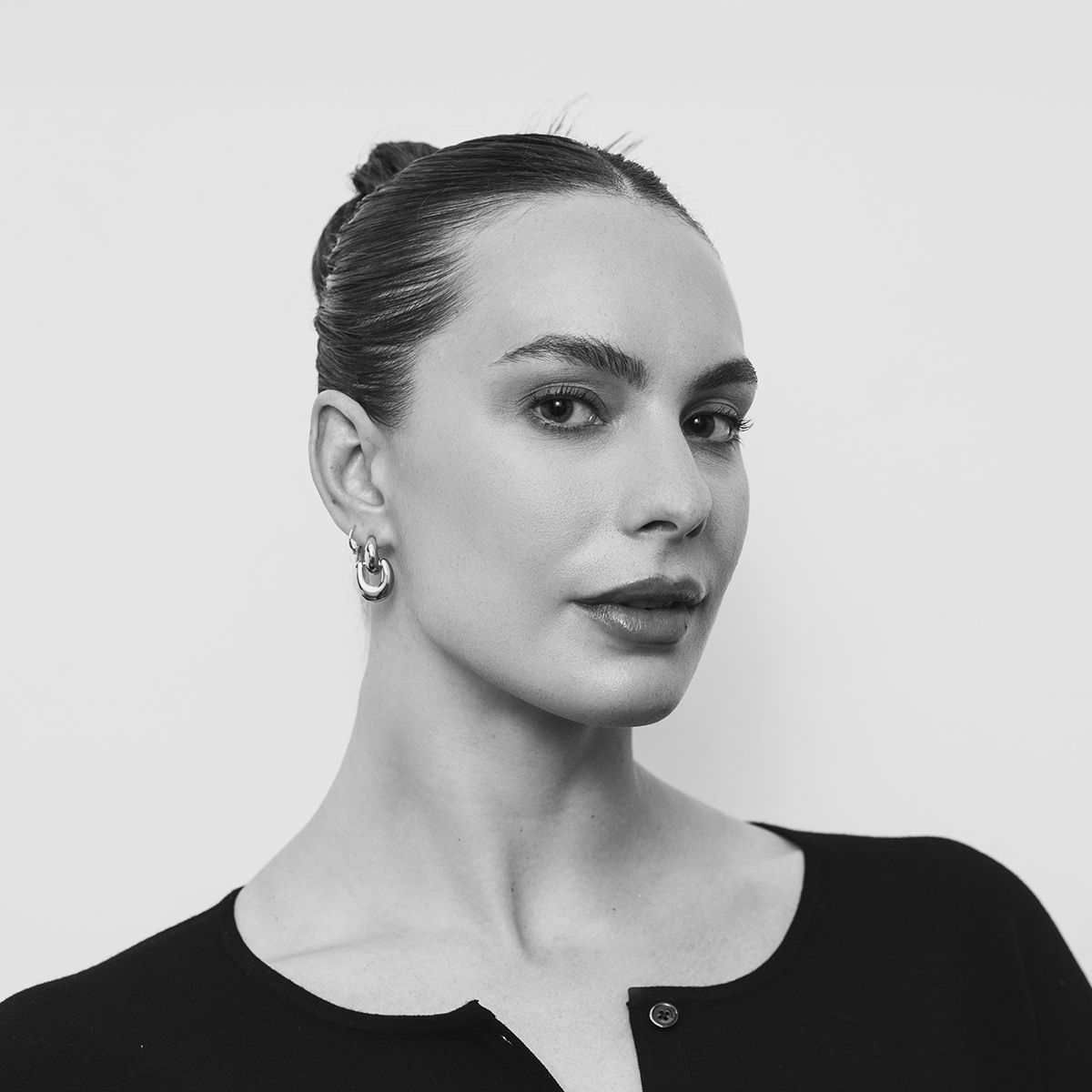 Penny Olesiak. Black and white headshot of Penny Olesiak wearing a black top, posing in front of a bright white background.