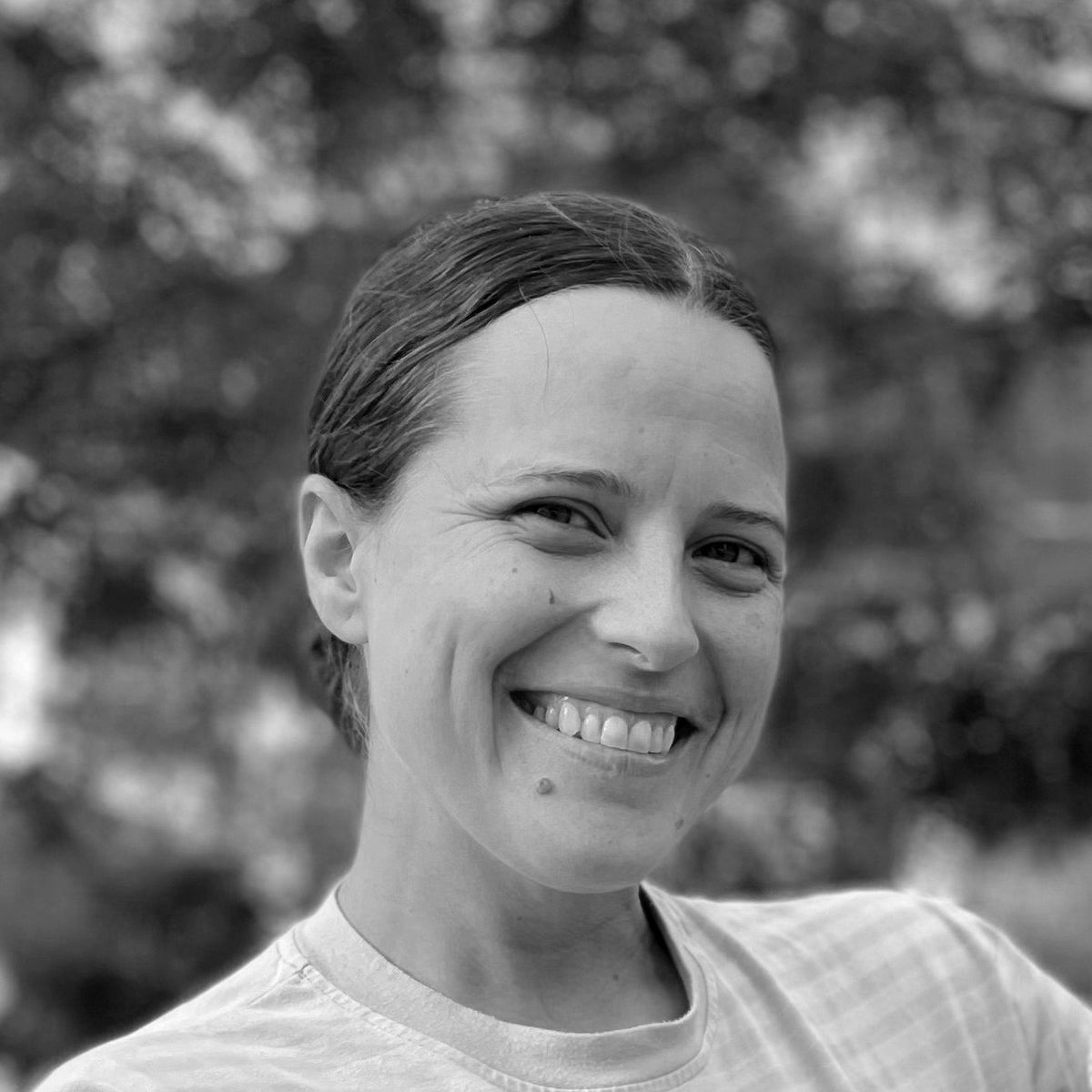 Lindsay Miles. Black and white headshot of Lindsay Miles posing outside and smiling.
