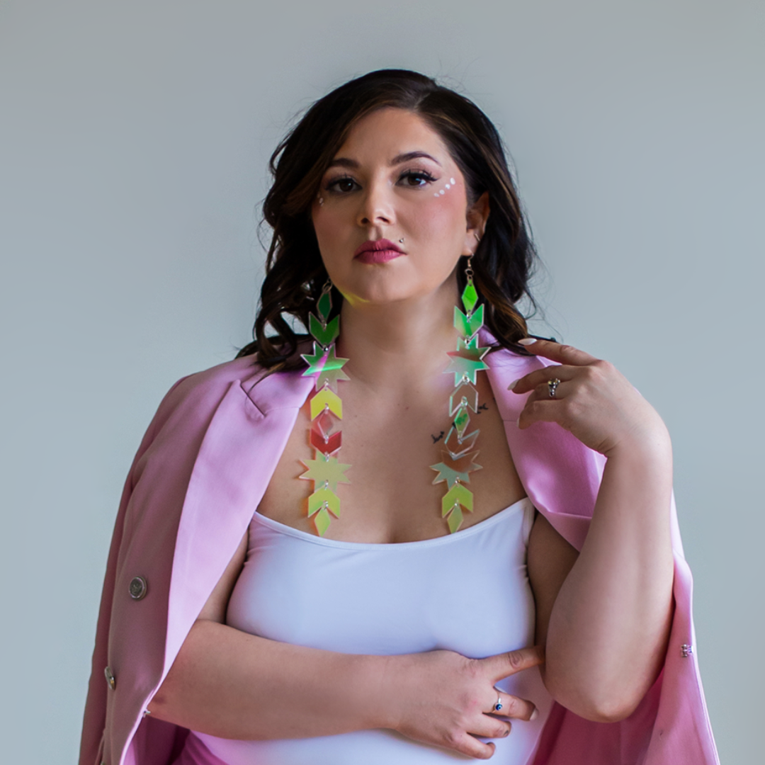 Headshot of Dr. Candace Linklater, speaker and founder, wearing a white top, bright pink blazer and long, colourful holographic earrings.
