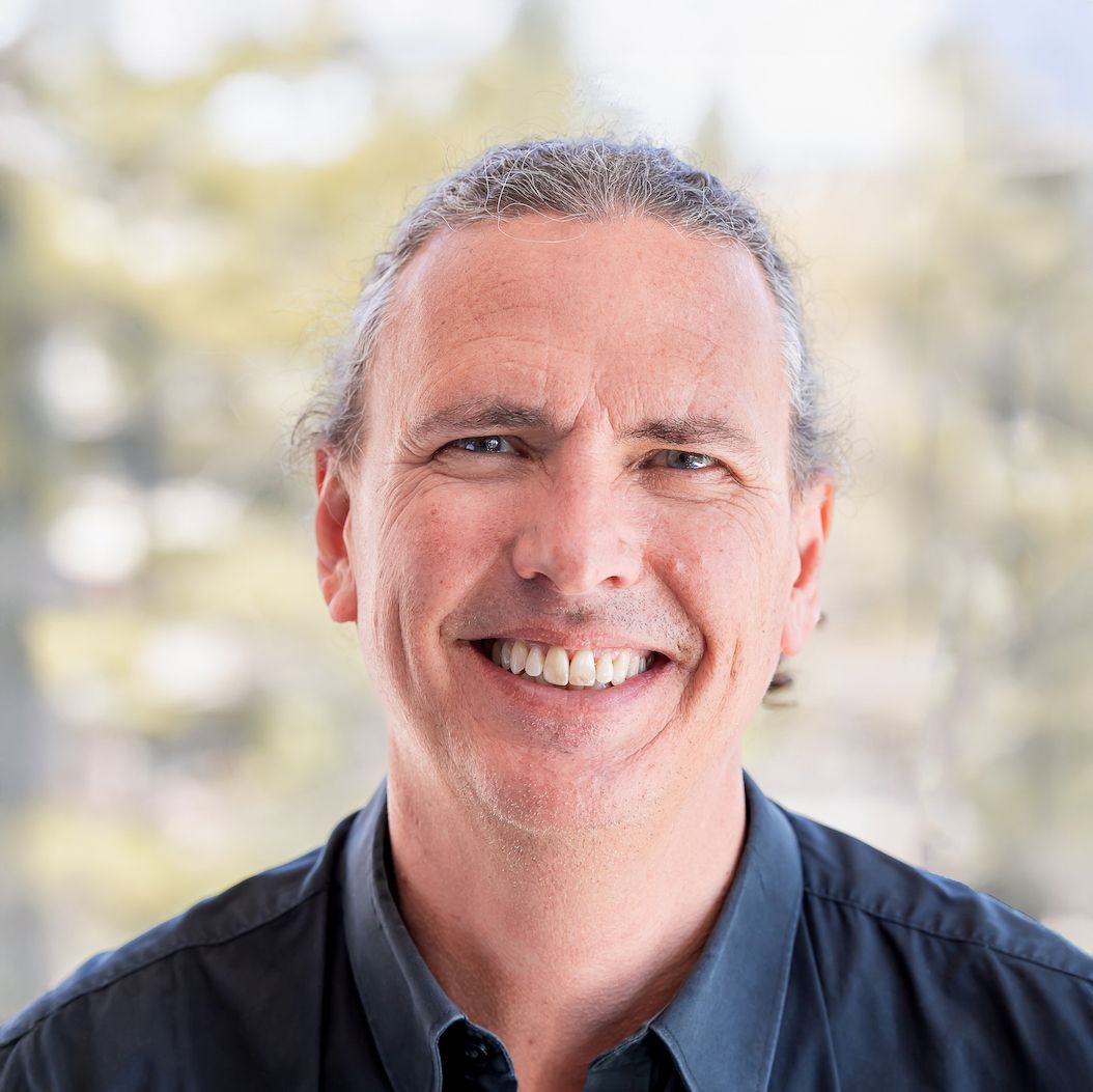 Steve Joordens. Headshot of Steve Joordens wearing a dark collared shirt and posing in front of a blurred outdoor background.