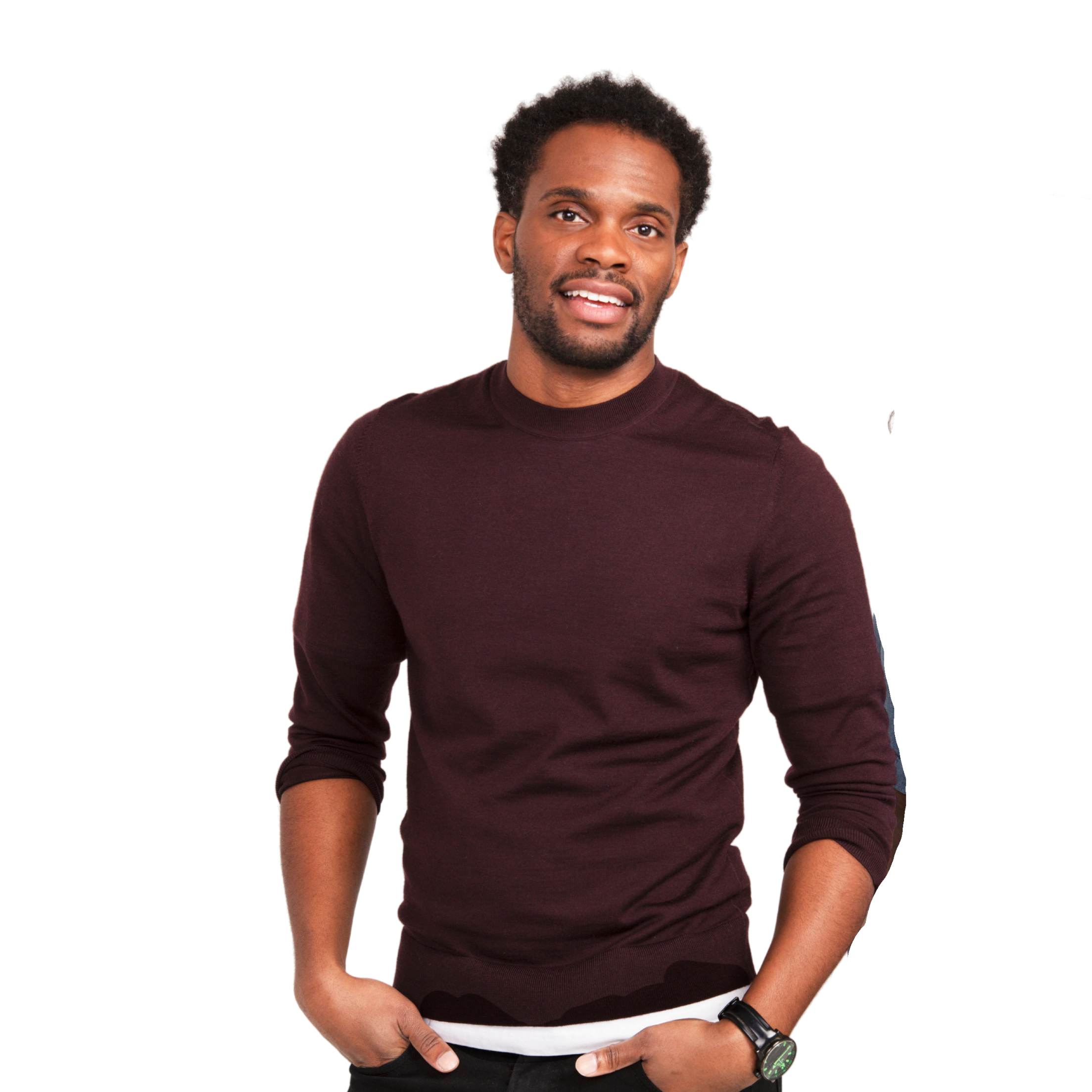 Headshot of Anthony Morgan, standing in front of a solid white background, wearing a maroon long-sleeve, with his hands in his front pants pockets.